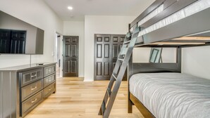 Una cama litera con escalera, un aparador y un espejo.