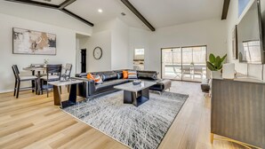 Un salón amplio con un sofá moderno, una mesa de comedor y un ventanal grande.
