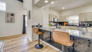 Una cocina moderna con una isla central, taburetes de bar y un comedor.