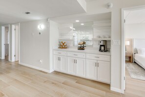 A modern kitchen with white cabinetry, a large mirror, and a coffee machine. - Stunning Views, Luxe Decor: Suntide III - Unit 805 (South Padre Island)