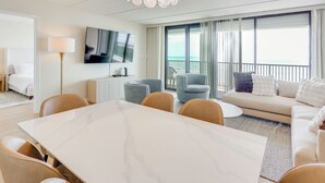 A modern hotel room with a dining area, a sofa, and a balcony with a view. - Stunning Views, Luxe Decor: Suntide III - Unit 805 (South Padre Island)