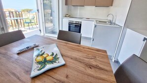 Un balcón con mesa y sillas, una cocina con armarios y electrodomésticos, y vistas al exterior.
