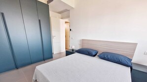 Un dormitorio moderno con una cama grande, un armario y una mesita de noche.