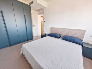 Ein modernes Schlafzimmer mit einem großen Bett, einem Kleiderschrank und einem Nachttisch.