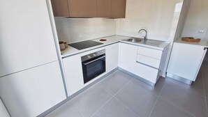 Una cocina compacta con muebles blancos, horno empotrado, estufa y pileta.