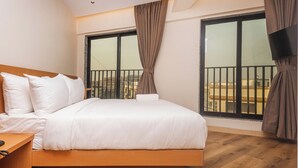 Un dormitorio con cama, suelo de madera, ventanas amplias y un balcón.