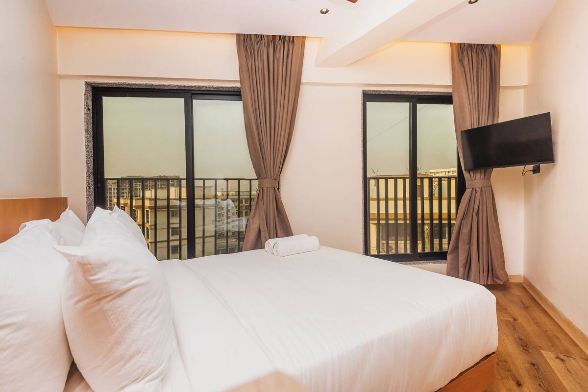 Ein Hotelzimmer mit Bett, Vorhängen, Fernseher und einem Balkon mit Blick.