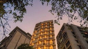 Un hotel de varios pisos con balcones, diseño arquitectónico moderno y vistas de edificios circundantes.