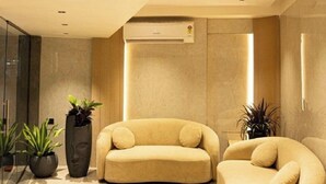 A modern interior with a beige sofa, a smaller armchair, and potted plants. - Rara Residence (Mumbai)