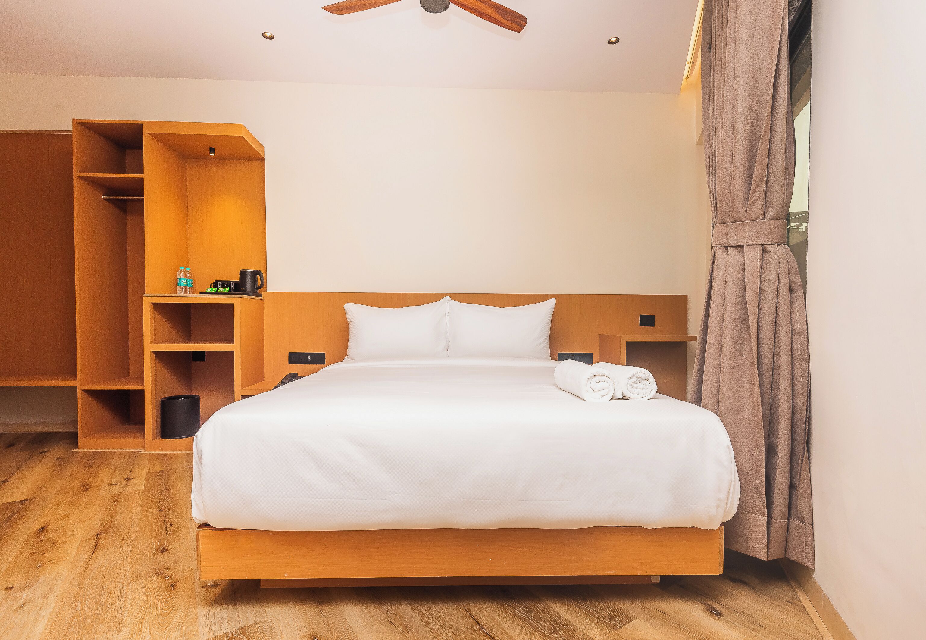 A hotel room with a wooden bed, a wardrobe, and a ceiling fan.