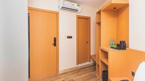Habitación de hotel con puertas de madera, un estante empotrado con cafetera, botellas de agua y un cesto de basura.