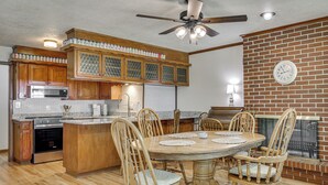 Una cocina con armarios de madera, un microondas empotrado y una zona de comedor con una mesa redonda y sillas.