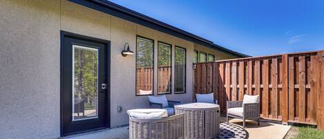 A patio with wicker furniture and a wooden fence.