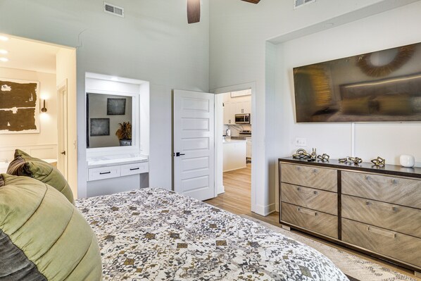 Un dormitorio con cama, cómoda y vista a la cocina.