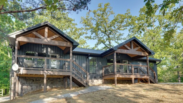 A two-story wooden cabin with a stone foundation, a balcony on the upper floor, and a covered deck area. - Walk to Kentucky Lake! Pet-Friendly Murray Duplex (Murray)