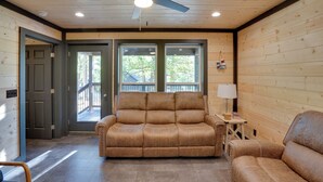 A room with a wooden ceiling, a ceiling fan, a sofa, a chair, a small table with a lamp, and a door leading outside. - Walk to Kentucky Lake! Pet-Friendly Murray Duplex (Murray)