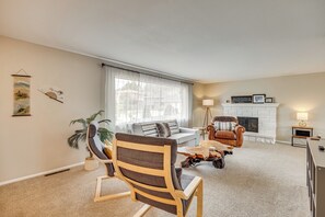 Ein Wohnzimmer mit einer Couch, einem Holzstuhl, einem Couchtisch, einem Kamin und einer Lampe.