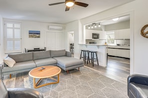 A modern living room with a sectional sofa, a round coffee table, and a ceiling fan. - < 1 Mi to Ocean! OBX Condo w/ Decks, Pets Welcome (Hatteras)