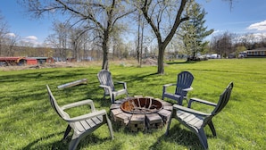 A grassy outdoor area with a fire pit and Adirondack chairs. - Dog-Friendly Waneta Lake Home w/ Lake Access! (Wayne)