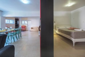A room with a bed, a dining table with chairs, a sofa, and a small table with a glass. - Elegant Urban Retreat in Psychiko 2 (Psichiko)