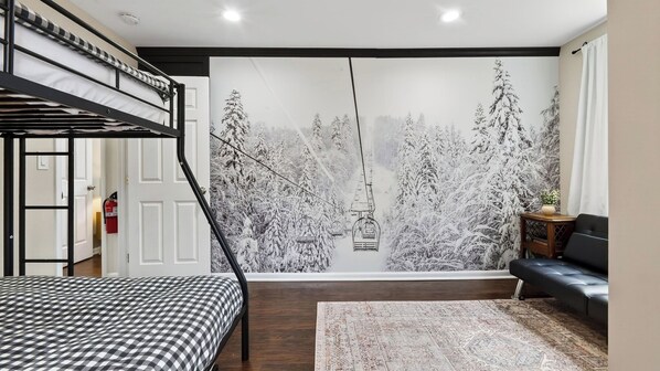 A bedroom with a bunk bed, a large window with a snowy forest mural, a sofa, and a rug. - Catskill Chalet by Avantstay Sleeps 22 Hot Tub + Firepit + Playroom Mins to Hunter Mtn (Tannersville)