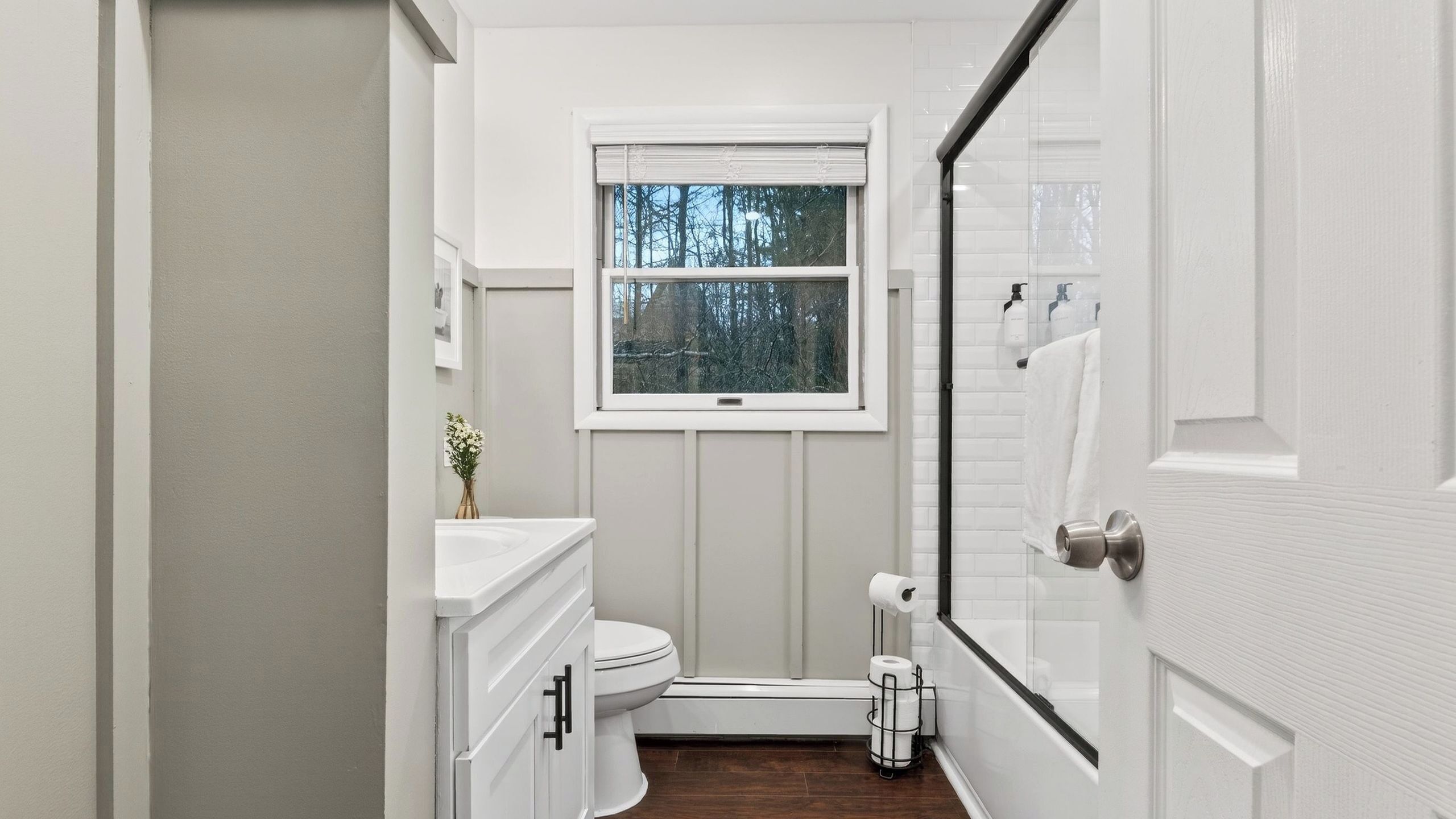 A narrow bathroom with a toilet, sink, and window.