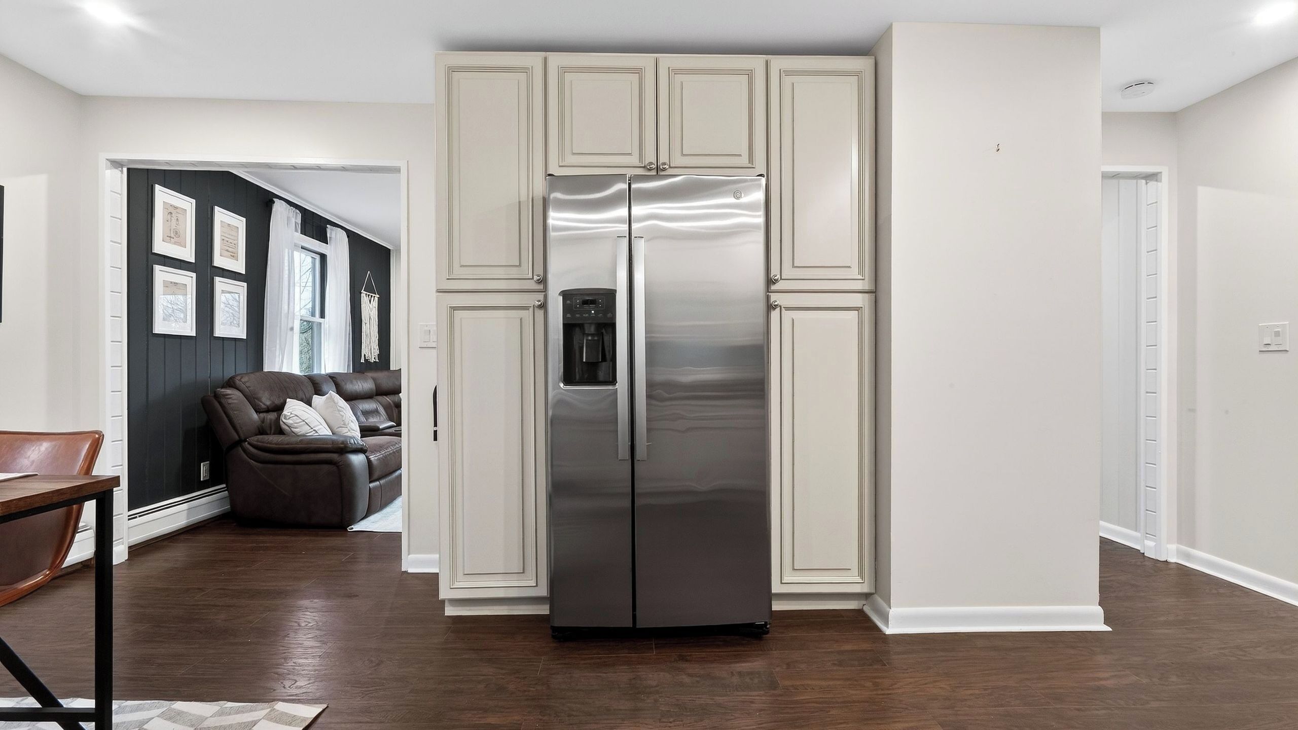 Una cocina moderna con refrigerador de acero inoxidable, armarios empotrados y piso de madera oscura.