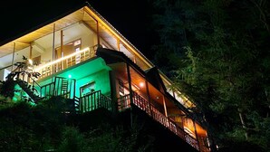 Ein mehrgeschossiges Gebäude mit Treppe, Balkon und einer beleuchteten Grünfläche.