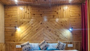 Ein Zimmer mit Holzwänden, einem Bett, Kissen und Blumentöpfen auf einem Holztisch.