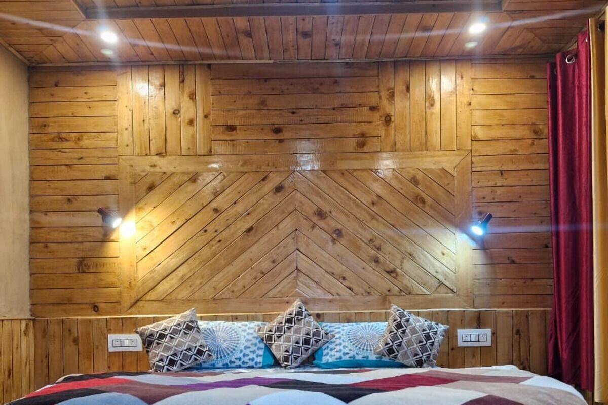Una stanza con pannelli in legno, un letto, cuscini e piante in vasi su un tavolo di legno.