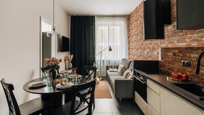 A modern kitchen with a brick wall, a dining area with a round table, and a sofa. - Skawinska Suites by Fragola Apartments (Kraków)