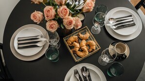 A table set for dining with plates, cutlery, glasses, and a box of pastries. - Skawinska Suites by Fragola Apartments (Kraków)