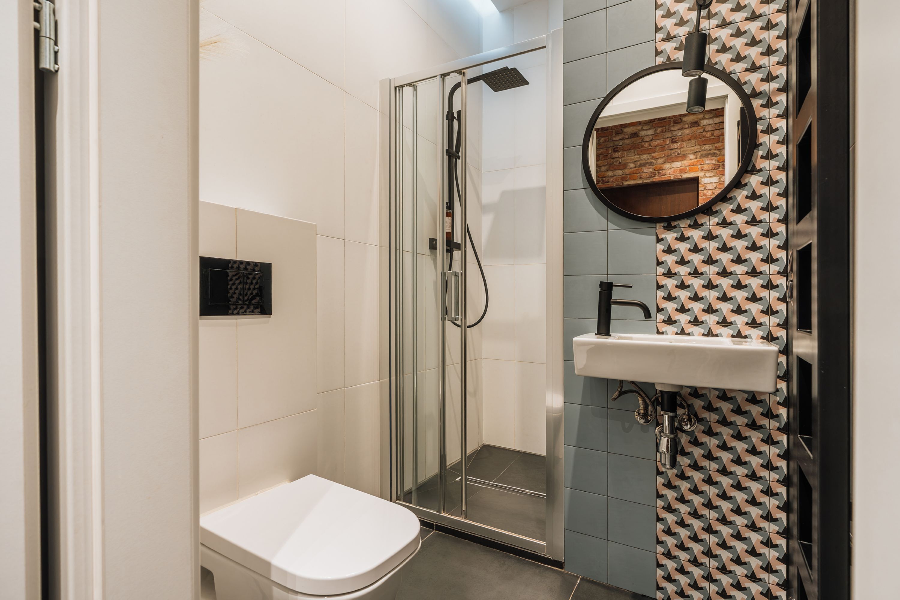 Une salle de bain moderne avec une douche à parois de verre, des toilettes blanches et un lavabo avec un miroir.