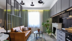 A modern living room with a sofa, a coffee table, a fireplace, and a kitchen area. - Skawinska Suites by Fragola Apartments (Kraków)