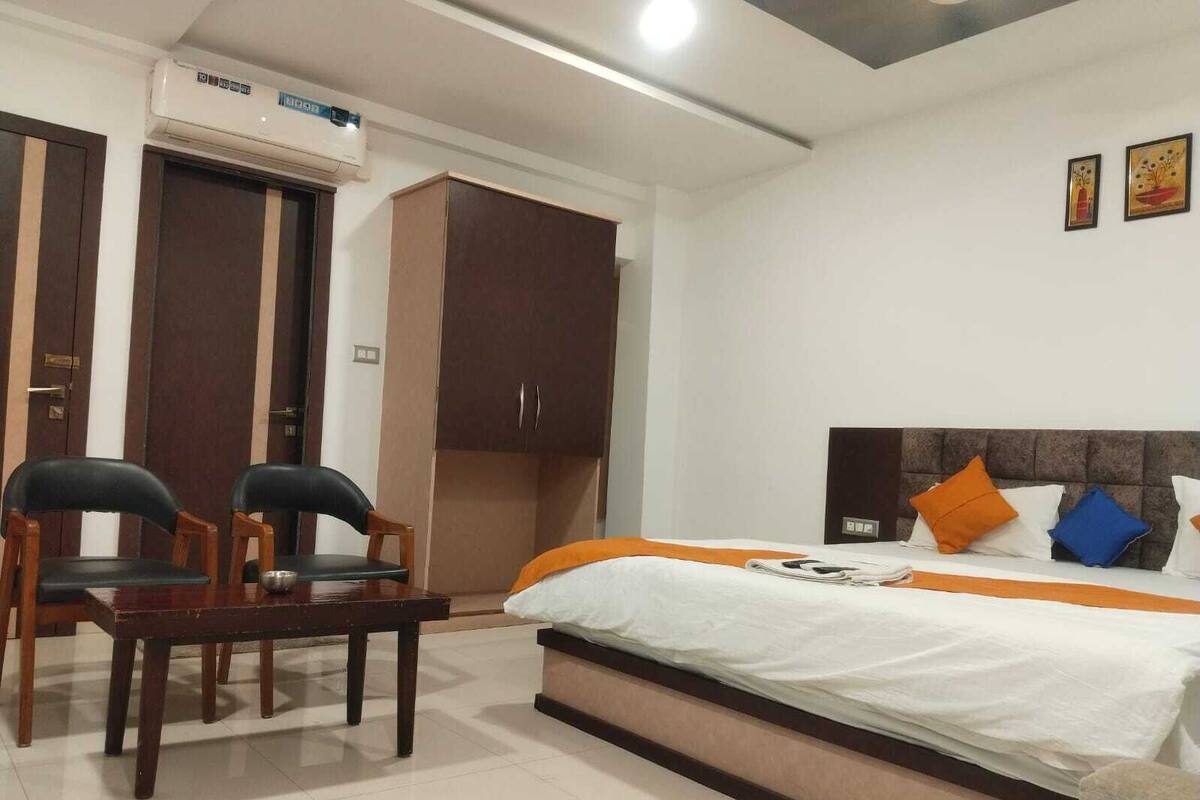 Ein Hotelzimmer mit Bett, zwei Stühlen, einem Kleiderschrank und einer Klimaanlage.