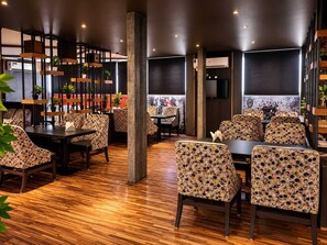 Un interior de restaurante con suelo de madera, sillas estampadas y mesas.