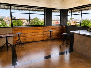 Un restaurante con vistas a la ciudad, paredes de madera y taburetes modernos.