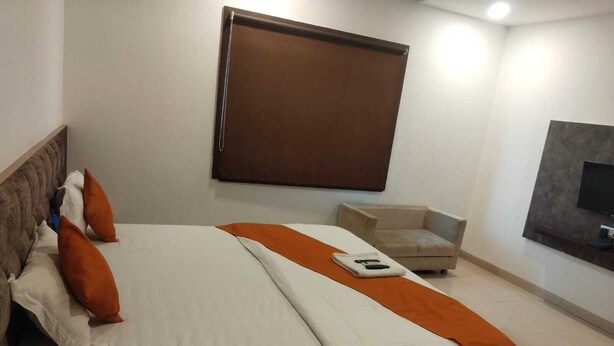 Ein Hotelzimmer mit Bett, Sessel, Fernseher und Fenster.