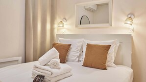 A neatly made bed with white and brown pillows, a rolled white towel, and a set of toiletries. - Lovely apartment with AC - Center of Paris (Paris)