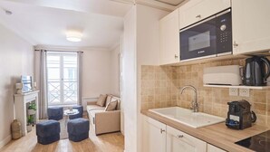 A compact kitchen with a Bosch microwave, a sink, and a coffee maker. There is a small seating area with a sofa and ottomans. - Lovely apartment with AC - Center of Paris (Paris)