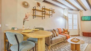 Un salon chaleureux avec une table à manger en bois, un canapé et un téléviseur fixé au mur.