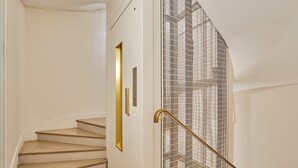 Un escalier avec une rampe en métal et une porte blanche dotée d’une poignée dorée.