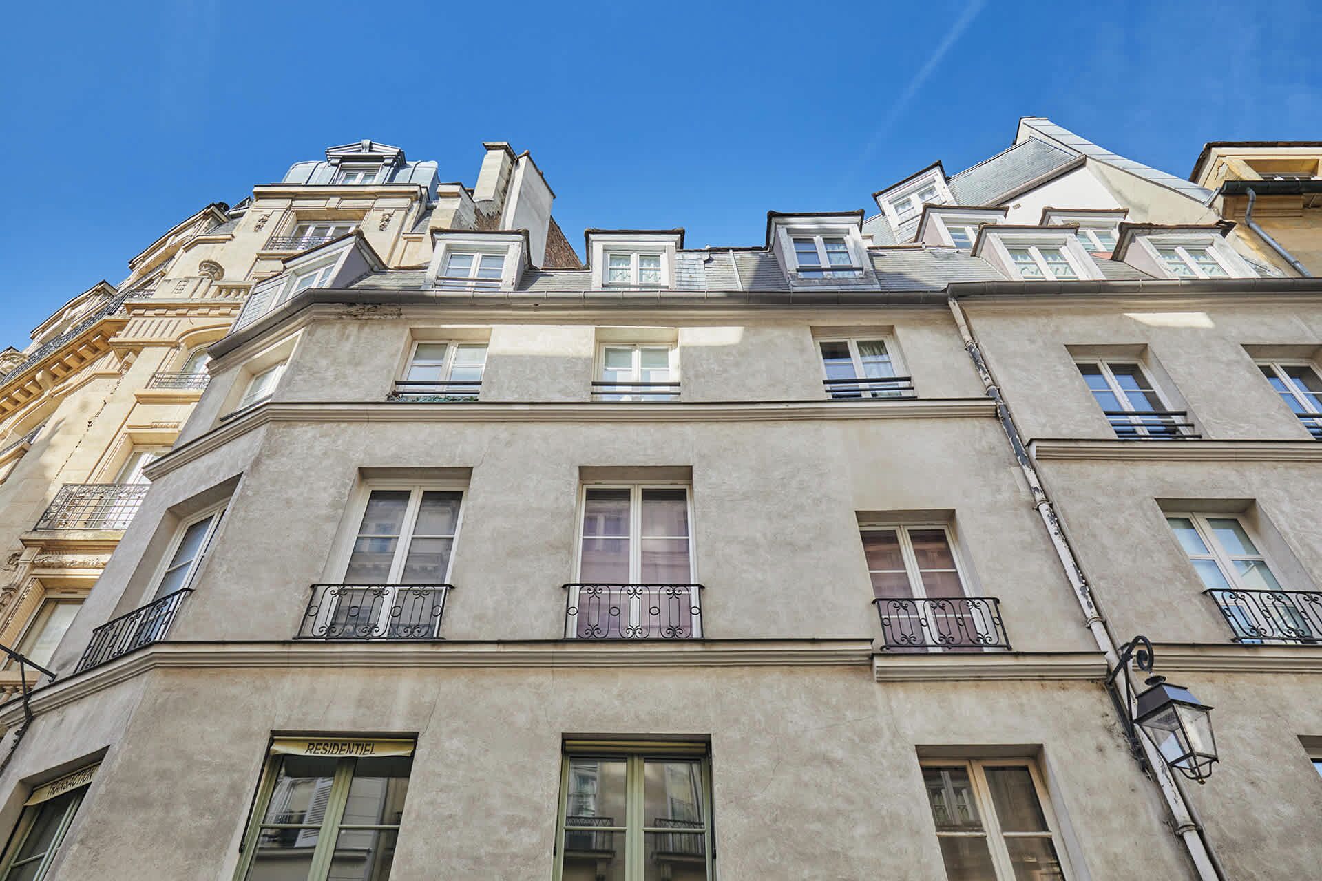 A multi-story building with balconies, large windows, and a clear sky.