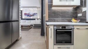 A modern kitchen with a Bosch oven, a refrigerator, and a white sofa in the background. - Spacious 6-bedroom villa in gorgeous Králův Dvůr with fitness room and terrace (Králův Dvůr)