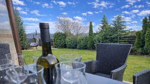 An outdoor dining area with wicker chairs, a table, wine glasses, and a bottle. - Spacious 6-bedroom villa in gorgeous Králův Dvůr with fitness room and terrace (Králův Dvůr)