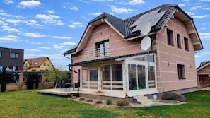 Una casa de dos pisos con balcón, antena parabólica y un patio cubierto.
