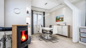 A modern kitchen with a built-in wood stove, white cabinetry, and a dining area with chairs and a table. - Spacious 6-bedroom villa in gorgeous Králův Dvůr with fitness room and terrace (Králův Dvůr)