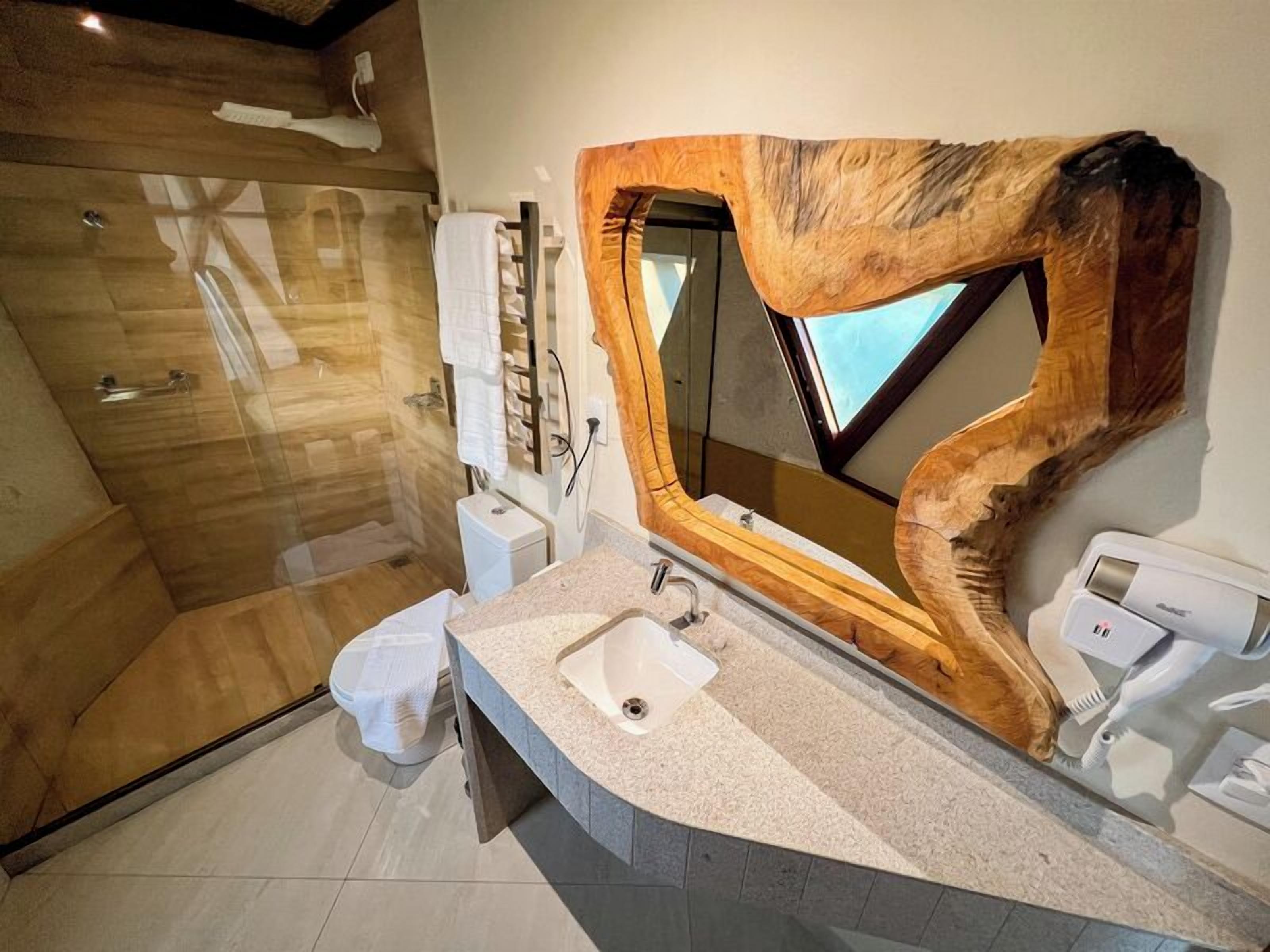 A modern bathroom with a large mirror, a shower, and a sink.