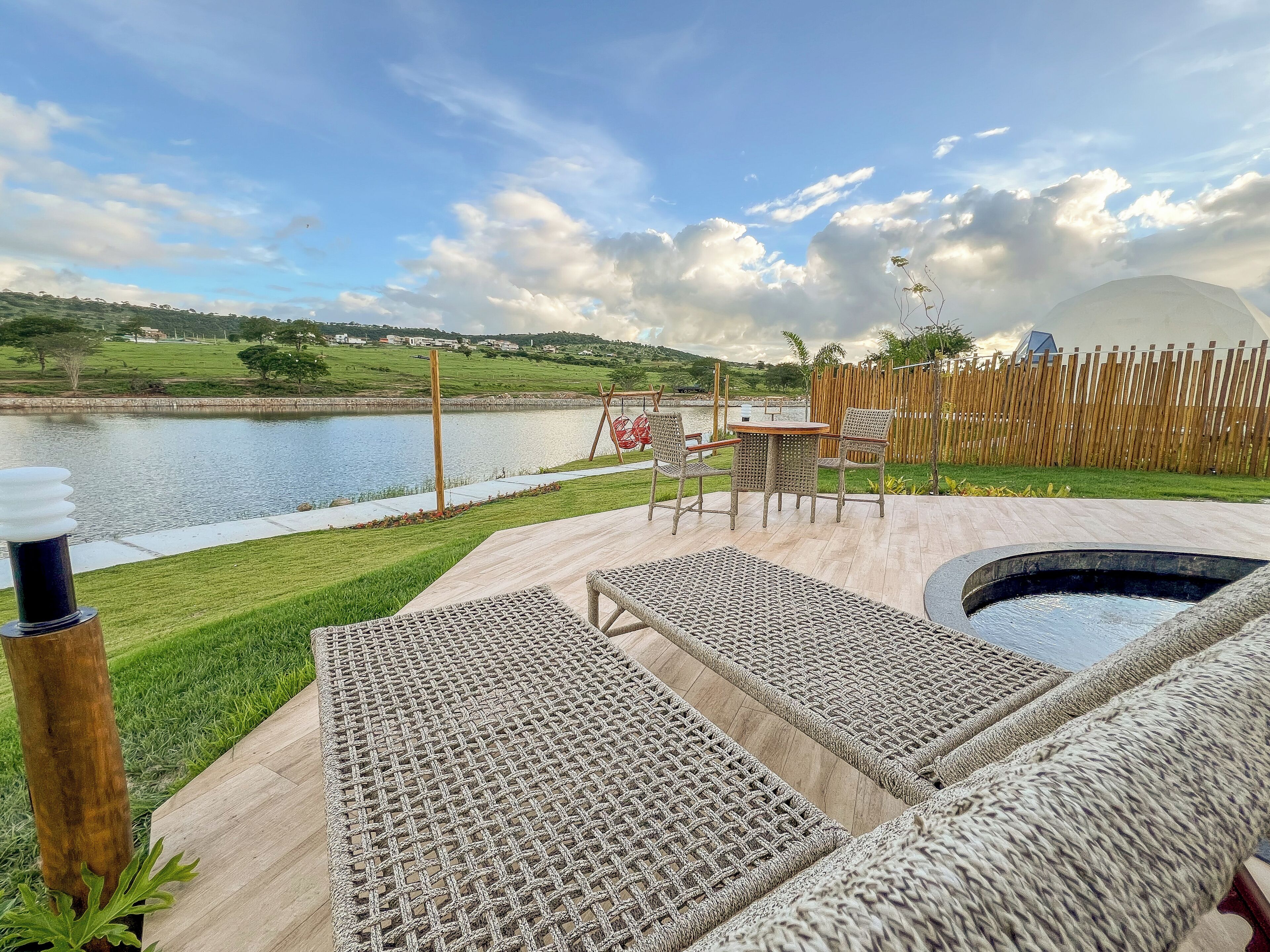 Un patio con piscina, muebles de mimbre y vista al lago.