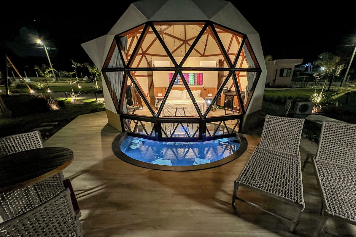 Una estructura hexagonal con una piscina en el centro, rodeada de asientos al aire libre.